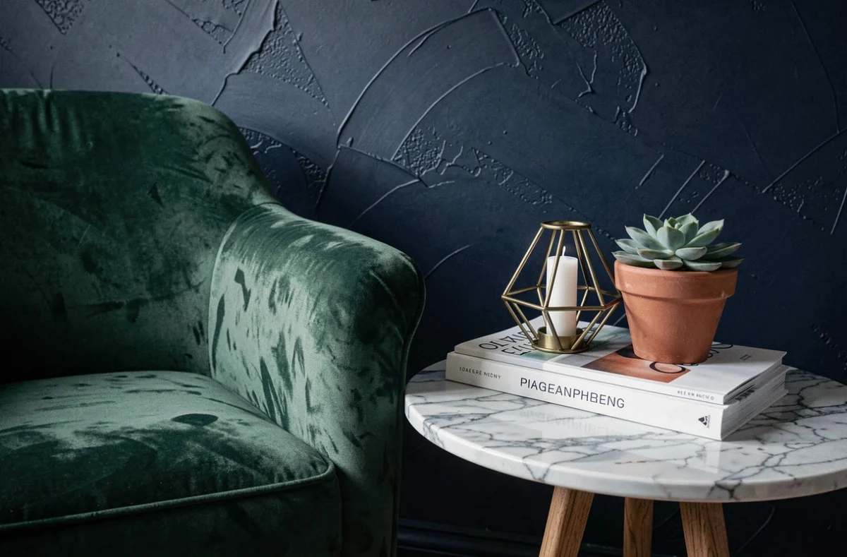 Coin lecture cosy avec fauteuil en velours vert forêt, table en marbre et décoration de style intérieur sombre et élégant